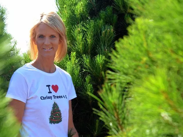 Debbie Bunker, in her white "I love Chrissy Trees 4 U" t-shirt standing beside her trees